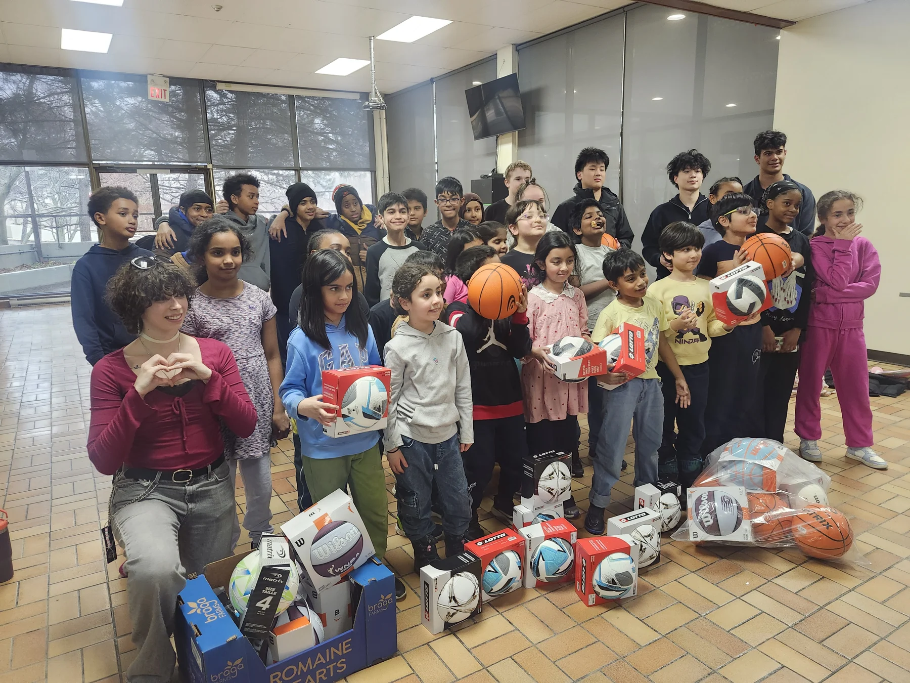 Children and PassNPlay volunteers with donated sports equipment at the Kick Start program